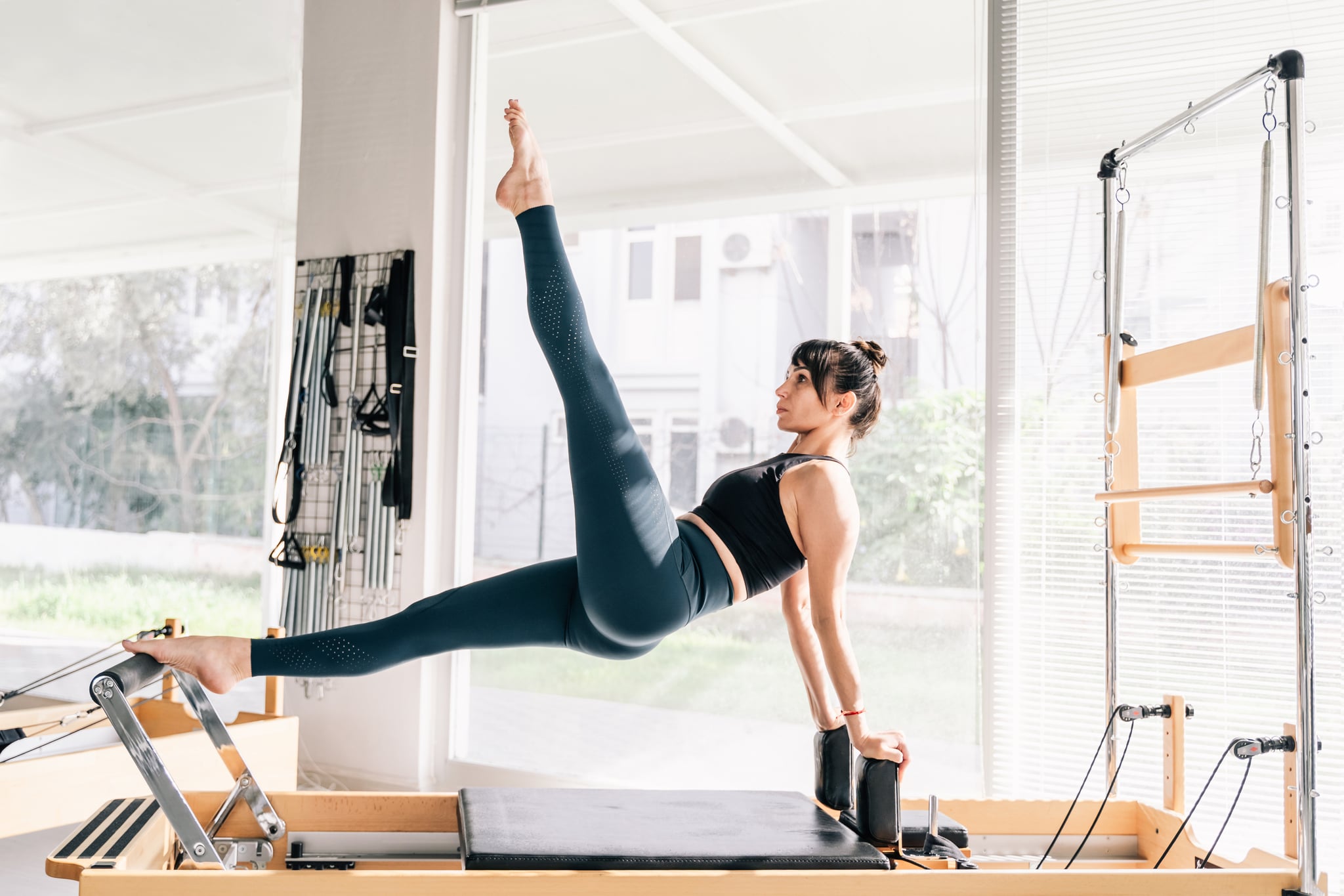Woman doing Pilates on reformer machines on a sunny day.