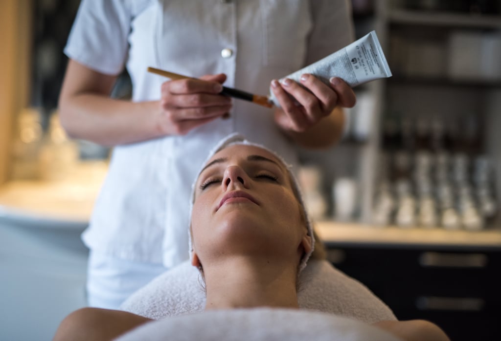 Will It Be Safe to Get a Facial Again?
After your state announces that spas and salons are allowed to reopen their doors, you can expect the facilities near you to up their already-strict and lengthy safety protocols. "Facial rooms at quality skin-care clinics have always been a safe space," Marino told POPSUGAR. "Estheticians are required by law to adhere to medical grade sanitizing protocols. We use hospital-strength disinfecting solutions that kill bacteria, fungi, and viruses." Because of the nature of the job, this is not only important for customers, but also the skin specialists. "Generally speaking, facialists are hyper-sensitive to cleanliness," said Marino. "Not only do we want to protect our clients from all pathogens, but when you work in close proximity to clients all day, you really need to be protecting yourself to ensure your own health and safety." 
In addition to upping their sanitation measures, many spas are required to limit the number of clients allowed in the office at a given time and encourage people to regularly sanitize their hands. At Marino's office, they've gotten creative with new disinfectant measures. "My office has invested in UV lamps that disinfect and kill viruses on all surfaces, so this is one thing we're implementing to take extra care in the rooms between clients and overnight for the entire office," she said.
Should You Wear a Mask to Your Facial?
Much like dermatology appointments concerning your face, wearing a face covering for the full duration of a facial would be impossible, but that doesn't mean you should leave your mask at home. "[Employees] are required to wear masks, and then obviously, the client unmasks during the facial, while the facialist remains masked," said Marino. 
But clients will only be able to unmask after they've undergone a health check. This will most likely involve getting your temperature checked before you walk in the door. "And masks are required up until [clients] are in the bed for their facial," said Marino. After your appointment has concluded, the mask must go back on and you'll be on your way. (A small inconvenience for your health.)
POPSUGAR aims to give you the most accurate and up-to-date information about the coronavirus, but details and recommendations about this pandemic may have changed since publication. For the latest information on COVID-19, please check out resources from the WHO, CDC, and local public health departments.