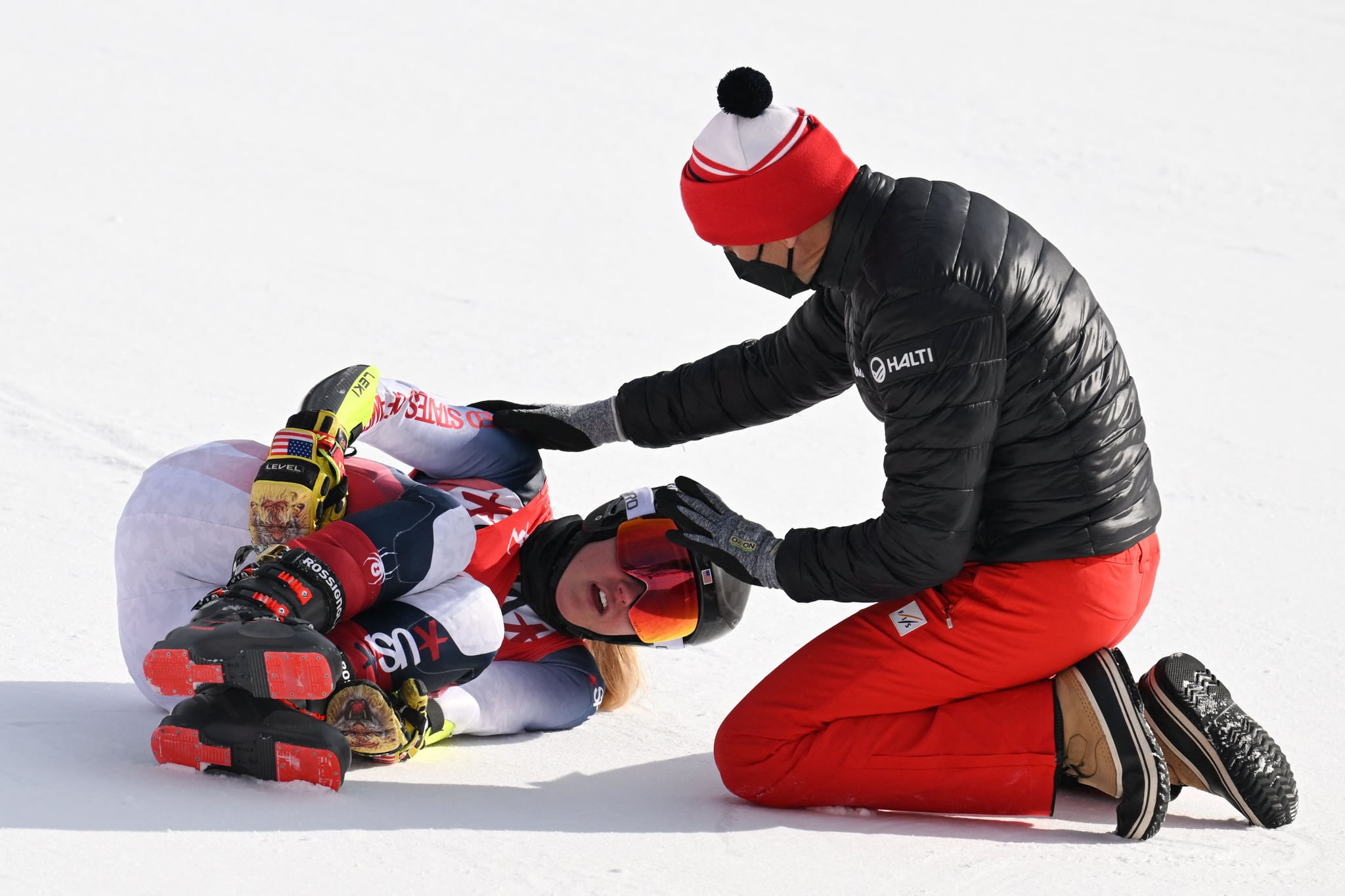 A medical staff member tends to USA's Nina O'Brien after she crashed in the second run of the women's giant slalom during the Beijing 2022 Winter Olympic Games at the Yanqing National Alpine Skiing Centre in Yanqing on February 7, 2022. (Photo by Fabrice COFFRINI / AFP) (Photo by FABRICE COFFRINI/AFP via Getty Images)