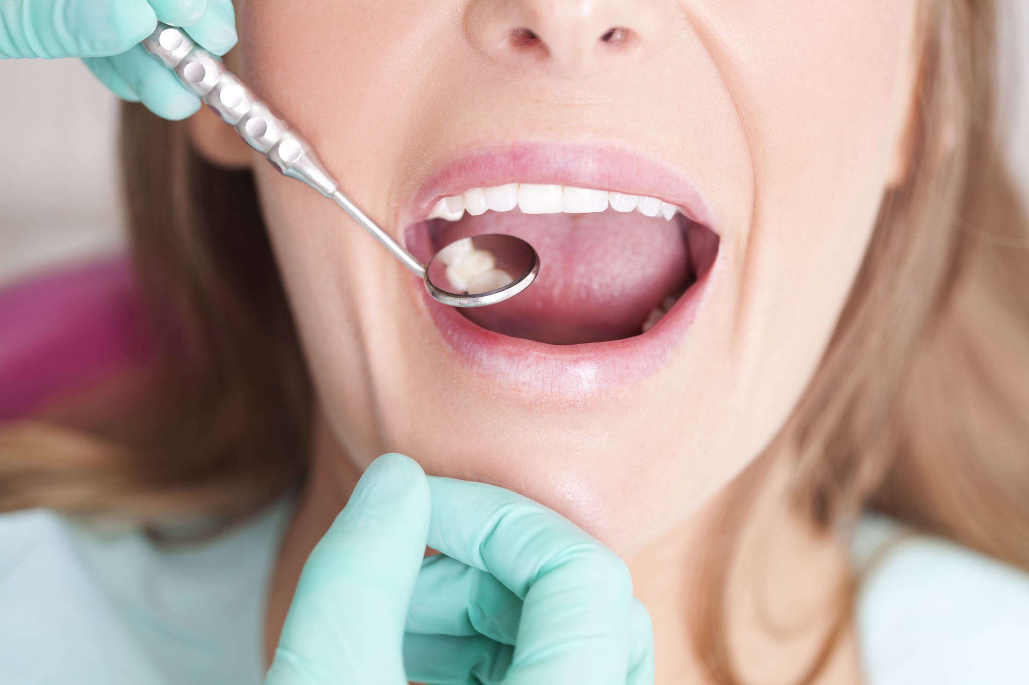 Female patient with open mouth  receiving dental inspection at dentist's office