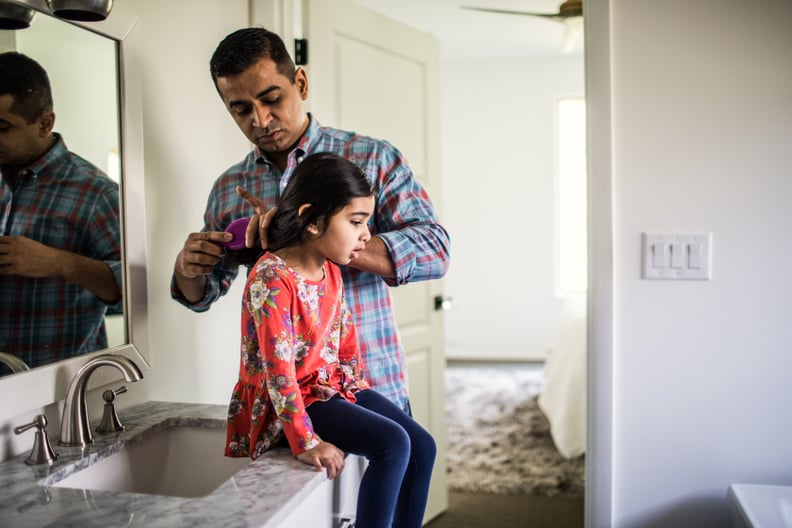 Father brushing daughters hair in bathroom