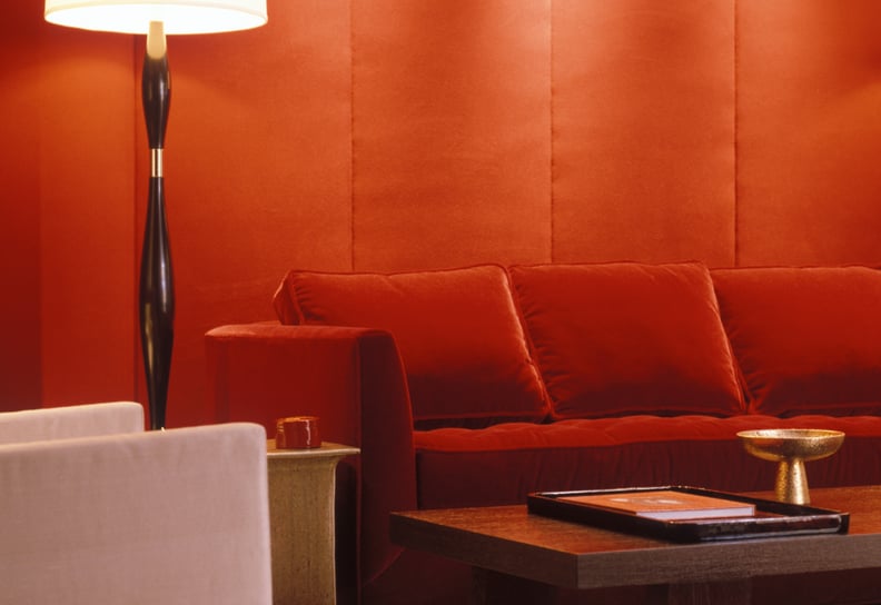a red velvet couch backdropped by a red wall