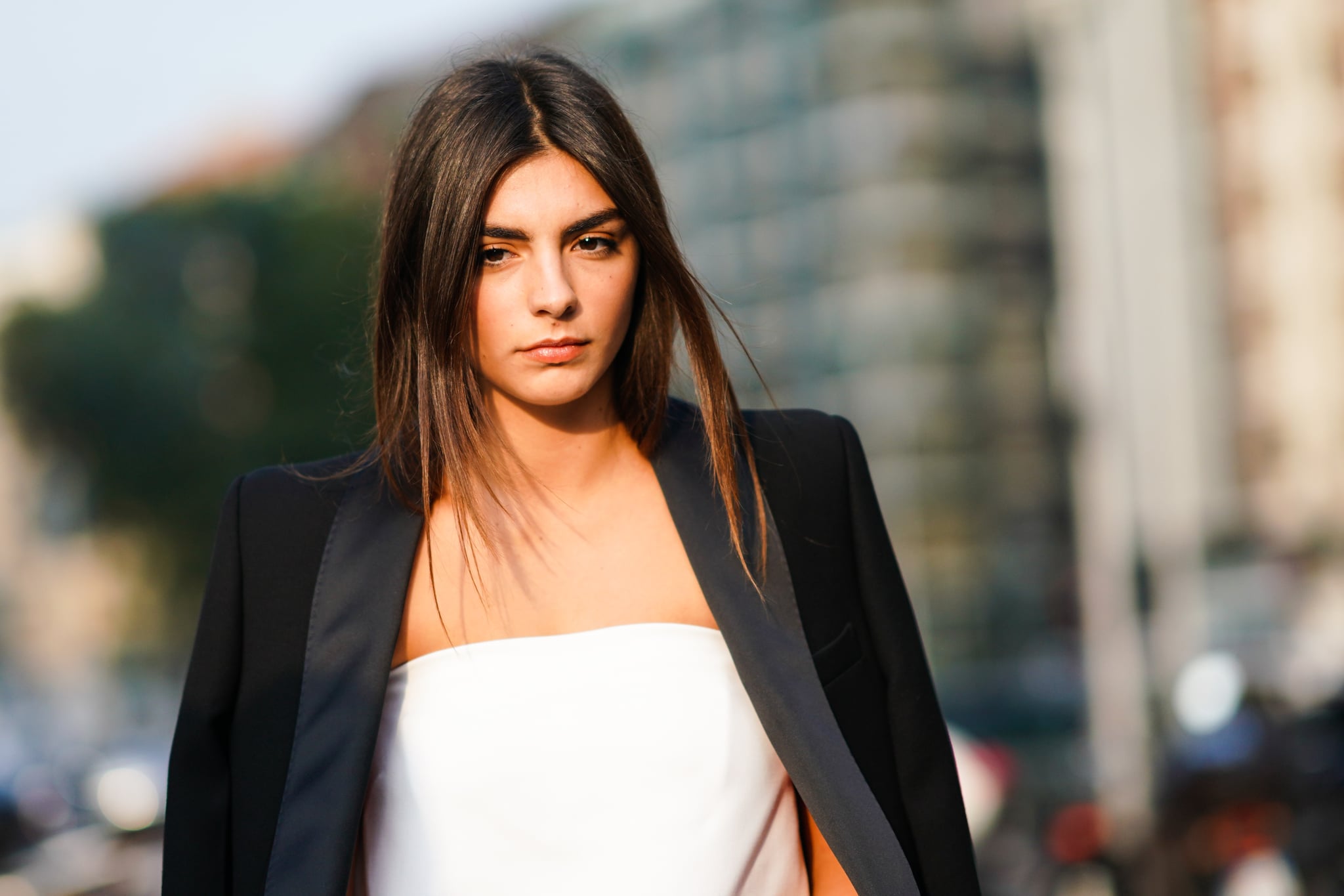 MILAN, ITALY - SEPTEMBER 18: A guest wears a black jacket and a white dress, outside the Alberta Ferretti show during Milan Fashion Week Spring/Summer 2020 on September 18, 2019 in Milan, Italy. (Photo by Edward Berthelot/Getty Images)