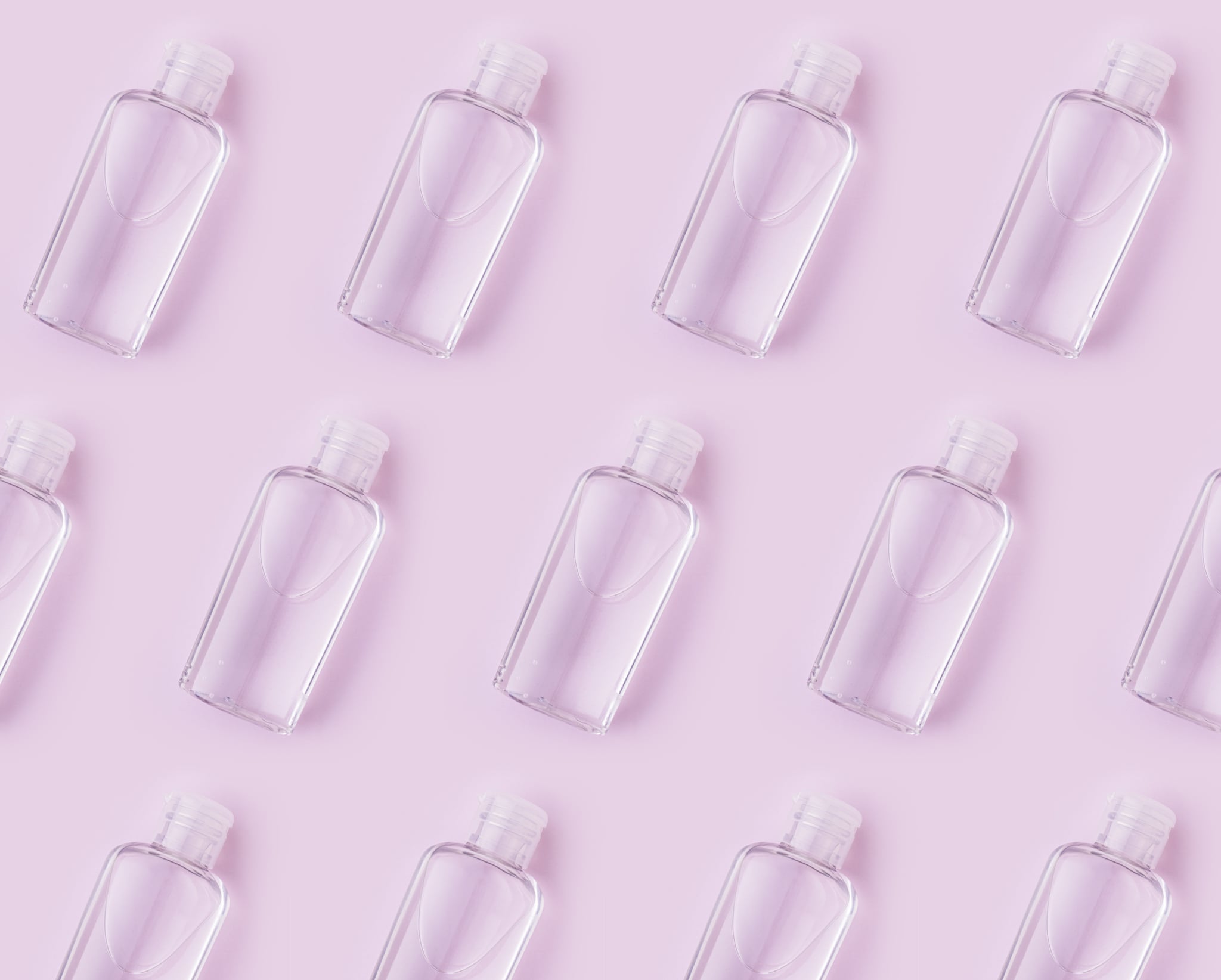 Hand sanitizer or soap bottles over pink background, making a pattern.