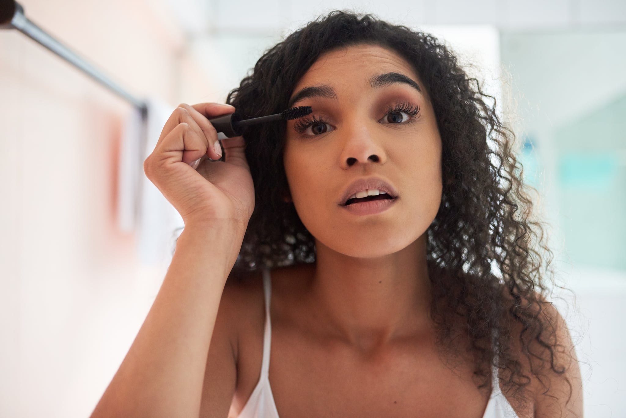 Portrait of an attractive young woman applying mascara in the bathroom