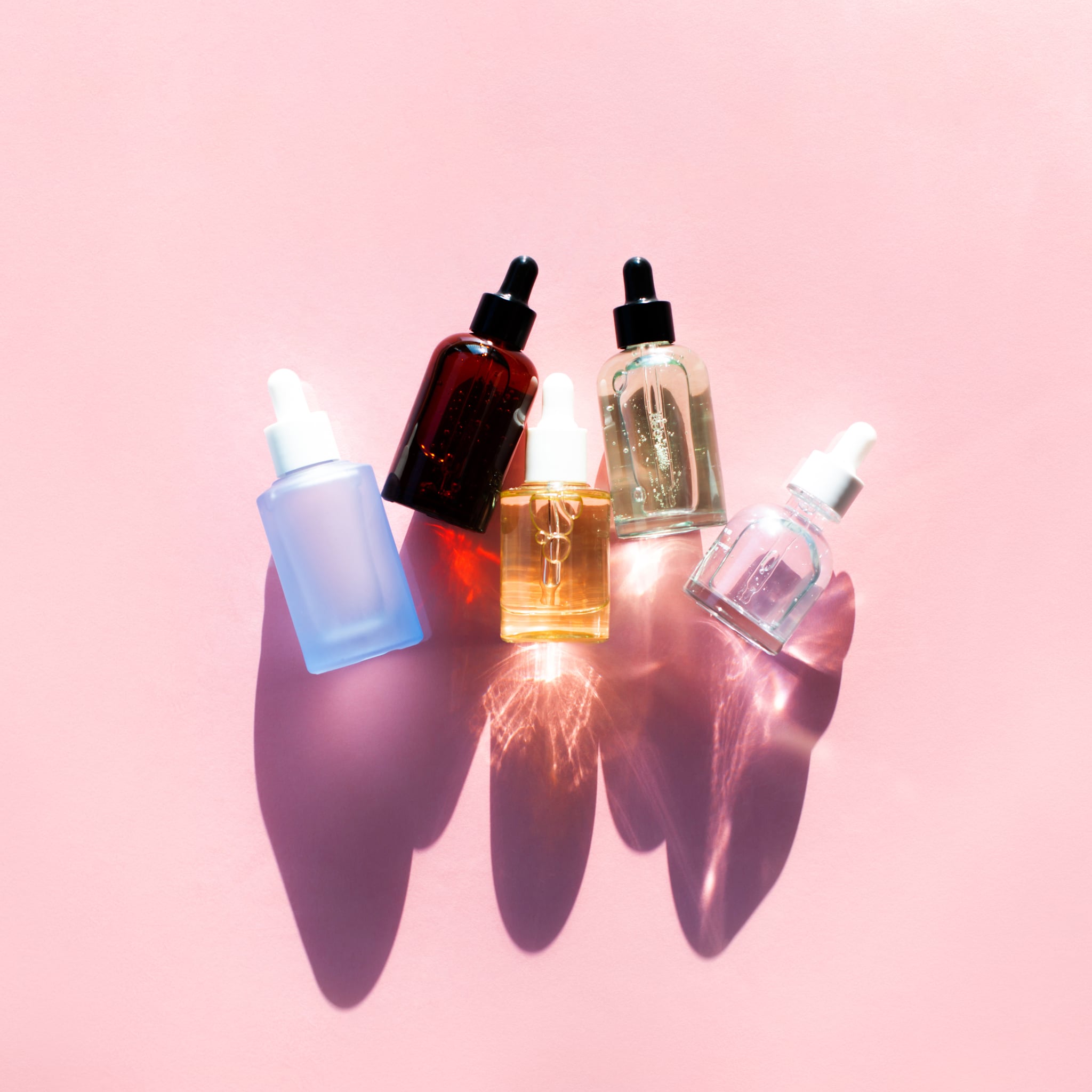 Top view of bottles of moisturizing cosmetic products arranged in line on pink background. Beauty product of the year