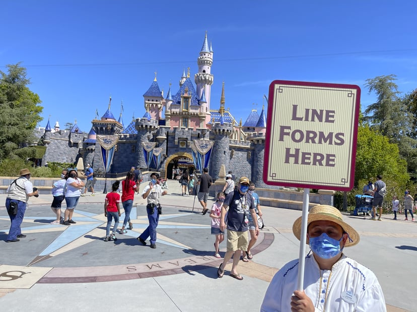 Anaheim, CA - April 30: A Disneyland employee forms a line for visitors to take pictures in front of Sleeping Beauty Castle in Anaheim, CA, on Friday, April 30, 2021. The resort