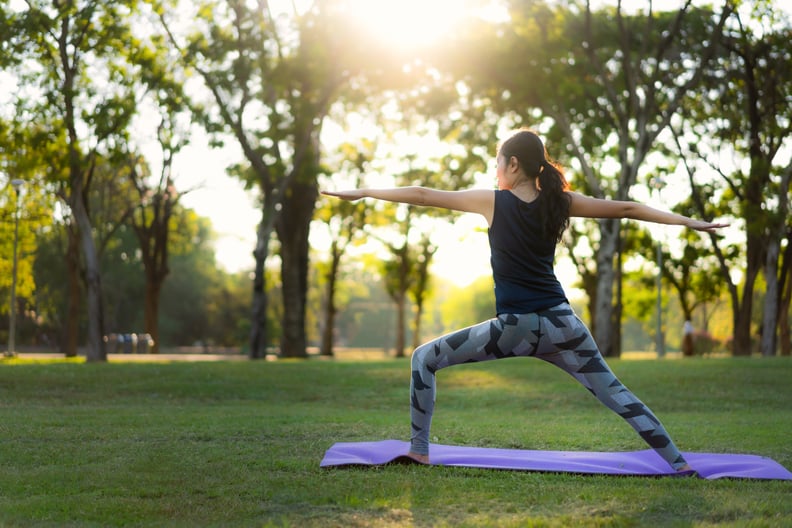Young Aisan woman practicing yoga in park at sunset.