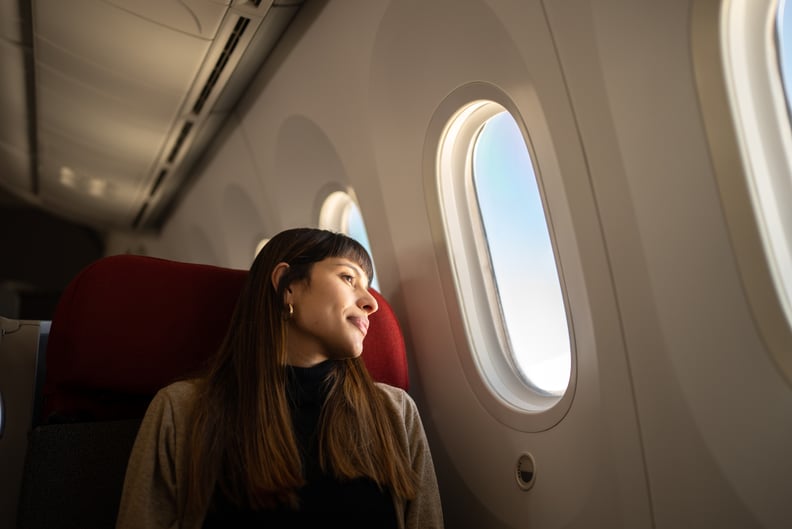 Young woman traveling by plane looking out the window.