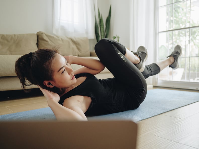 Young asian woman exercise at home with the help of online tutorials in living room.