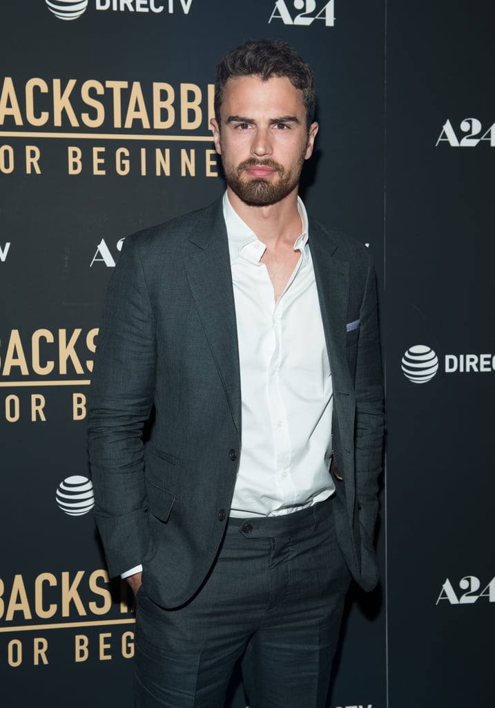 After waiting with bated breath for almost two years for Theo James to return to the red carpet, guys, it's finally happened! On Tuesday, the 33-year-old actor attended the NYC premiere of his new film, Backstabbing For Beginners, and he looked all sorts of hot. In addition to staring straight into our soul with his sexy smolder, Theo cut a suave figure in a dark suit and white button-down as he posed for the cameras with director Per Fly, producer Nikolaj Vibe Michelsen, and author Michael Soussan. The last time we saw Theo was at Comic-Con in NYC back in October 2016 — can you believe it's been that long? 
Even though Theo has been out of the spotlight, he's actually been busy working on new projects. In addition to Backstabbing For Beginners, he'll also be starring alongside Emily Ratajkowski in the thriller Lying and Stealing and alongside Christina Aguilera and Rashida Jones in the sci-fi romance Zoe. Um, excuse us while we try to pull ourselves together.