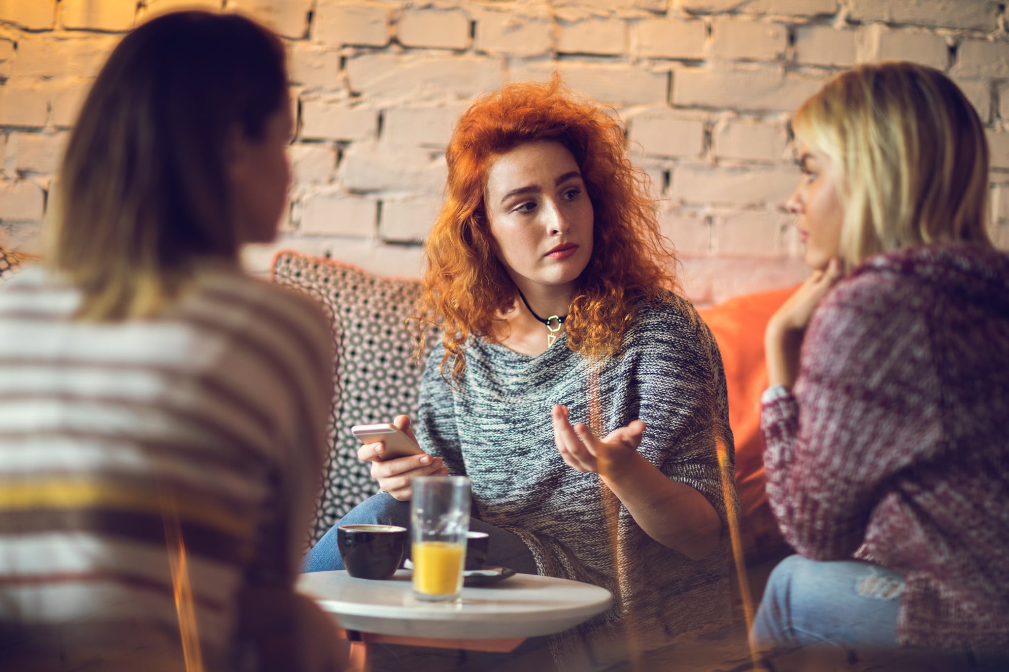 Young serious woman in a cafe communicating with her female friends.