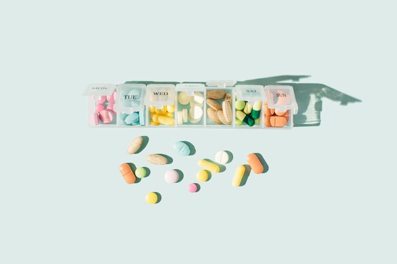 Box for pills and time-release capsules on blue background. Pills organizer with time-release capsules, tablets, vitamins, painkillers, medications and dietary supplements. Minimal medical, health care, pharmacology concept. Flat lay, top view.