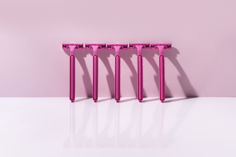 Five pink razor blades supported by a pink wall