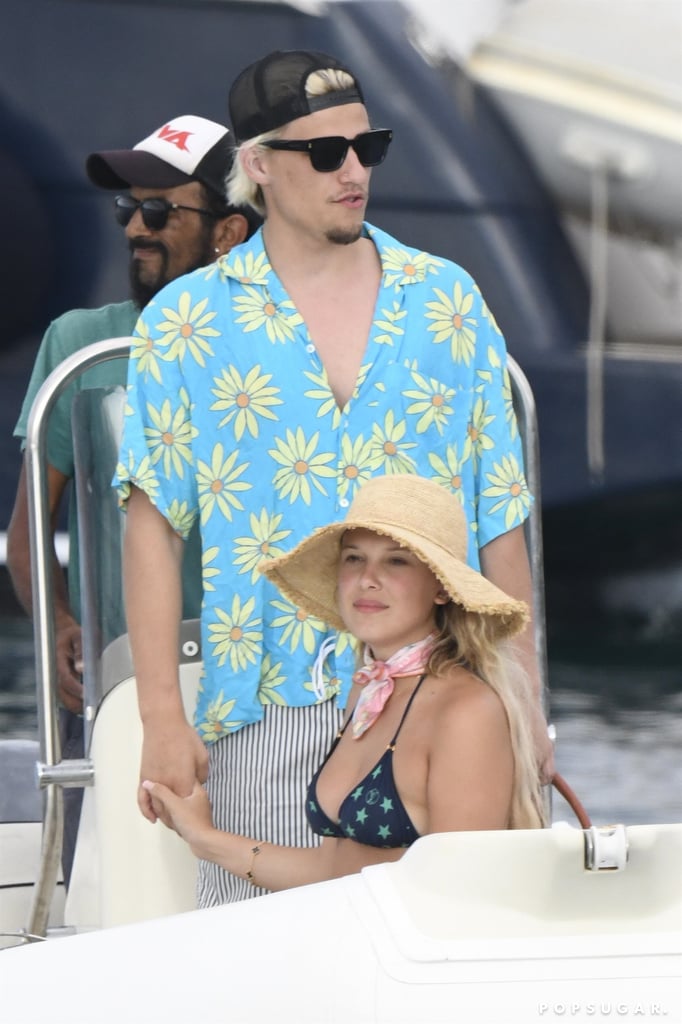 Millie Bobby Brown and Jake Bongiovi are enjoying some quality time in the sunshine during their Italian vacation. On July 4, the "Stranger Things" star and her beau were photographed in Sardinia, where they were seen exchanging some sweet kisses on a boat. Brown wore a black-and-white gingham two-piece bikini, and Bongiovi sported a simple pair of red Dior swim trunks. 
On July 8, they were spotted again as they lounged on a boat and took in the ocean views. Four days later, they soaked up the sun on the beach and had lunch together. Brown also sported a sparkly ring on that finger. 
Since subtly confirming their relationship in November 2021, Brown and Bongiovi have slowly been giving us more glimpses of their romance. The pair made their red carpet debut at the BAFTAs in March before stepping out again for the "Stranger Things" season four premiere on May 14.
However, it seems these two love to save the PDA for their vacations, as they both took to Instagram that same month to share a few loved-up snaps from their Barcelona trip. Brown wrote "te amo" alongside her photo series, while Bongiovi simply captioned his post, "Alexa play late night talking by Harry styles."
Ahead, see more photos from the couple's recent trip to Italy. 

    Related:

            
            
                                    
                            

            22 Photos That Perfectly Capture Millie Bobby Brown and Jake Bongiovi&apos;s Chemistry