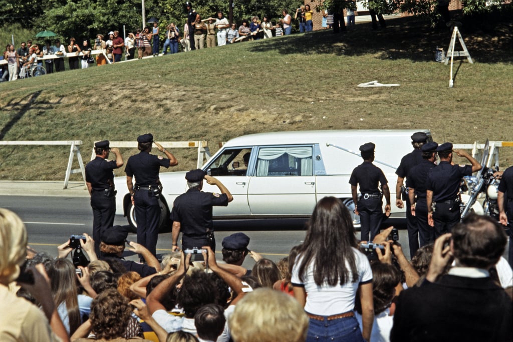 Police officers saluted as Elvis's casket was driven by in the procession.