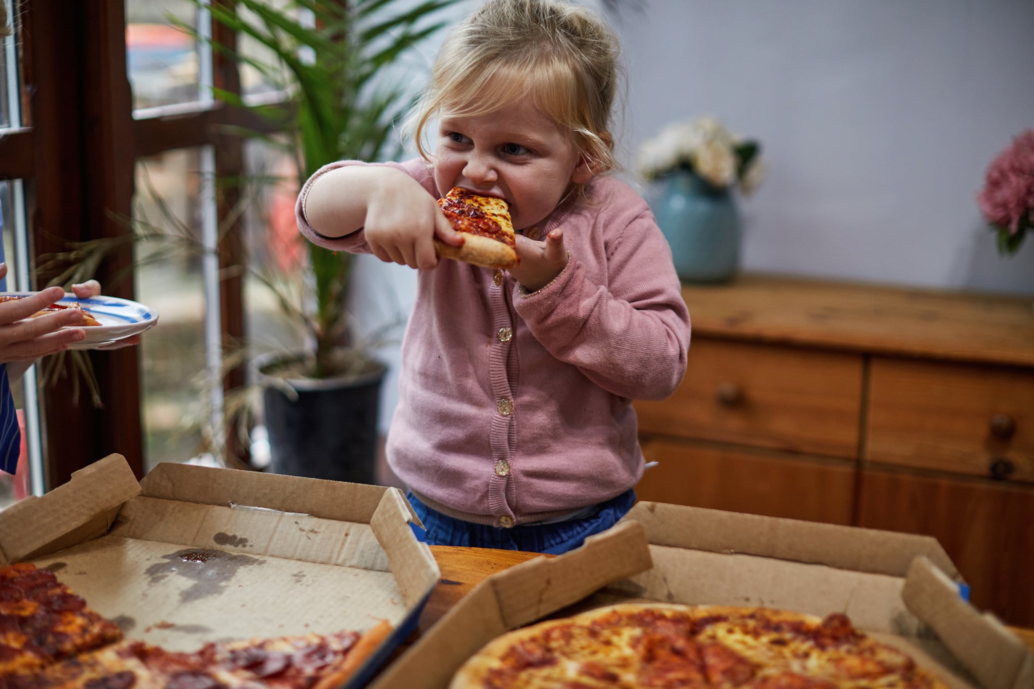 Toddler eating a slice of takeaway pizza