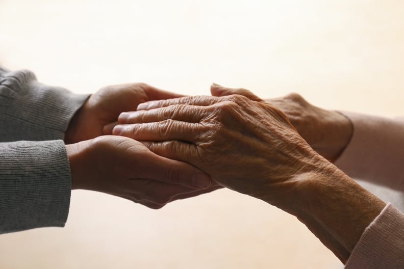 Cropped studio shot of elderly woman and female geriatric social worker holding hands. Women of different age comforting each other. Close up, background, copy space.