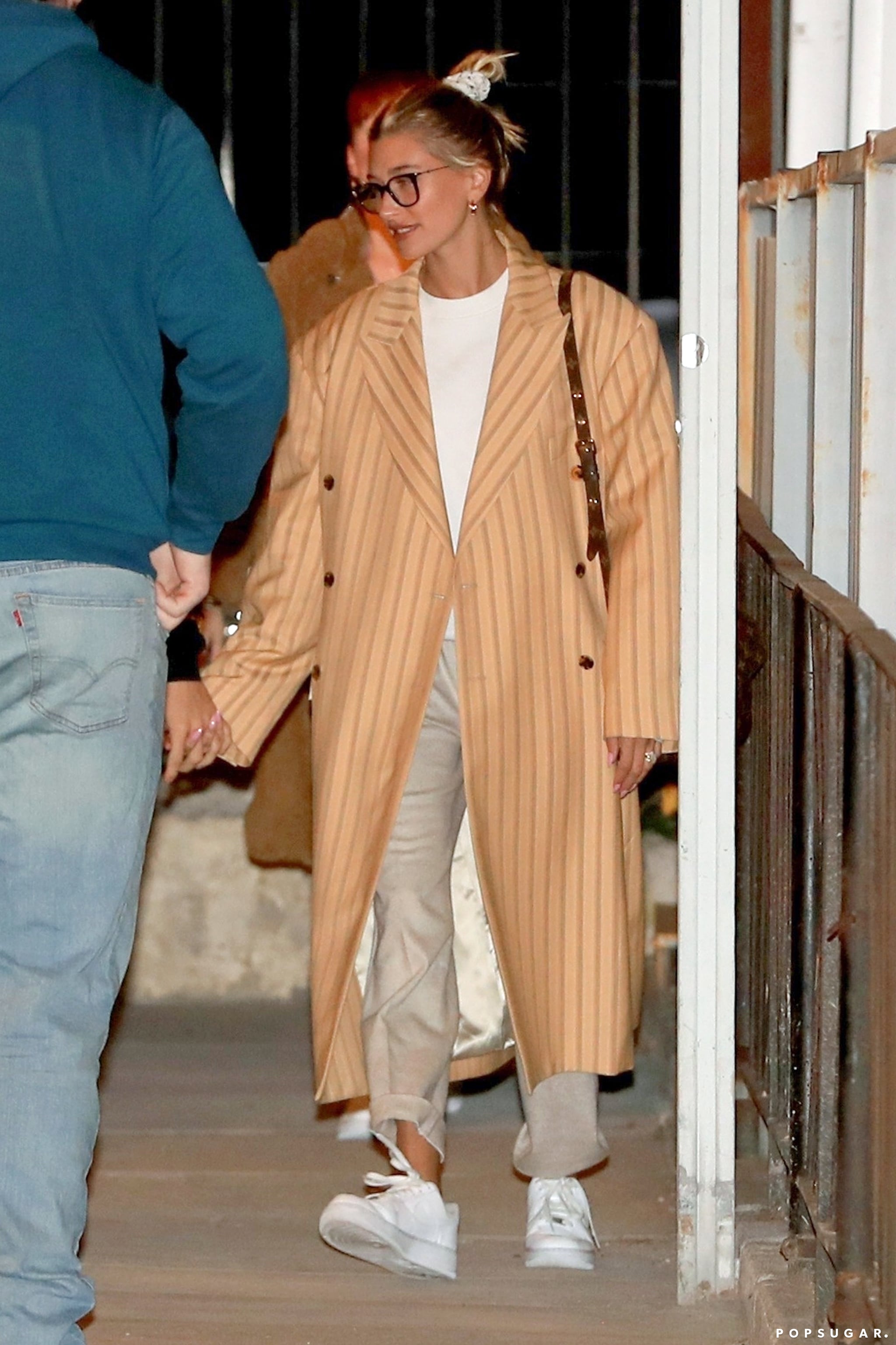 Hailey Bieber wears a beige long coat and Nike Air Force 1s as she steps out
