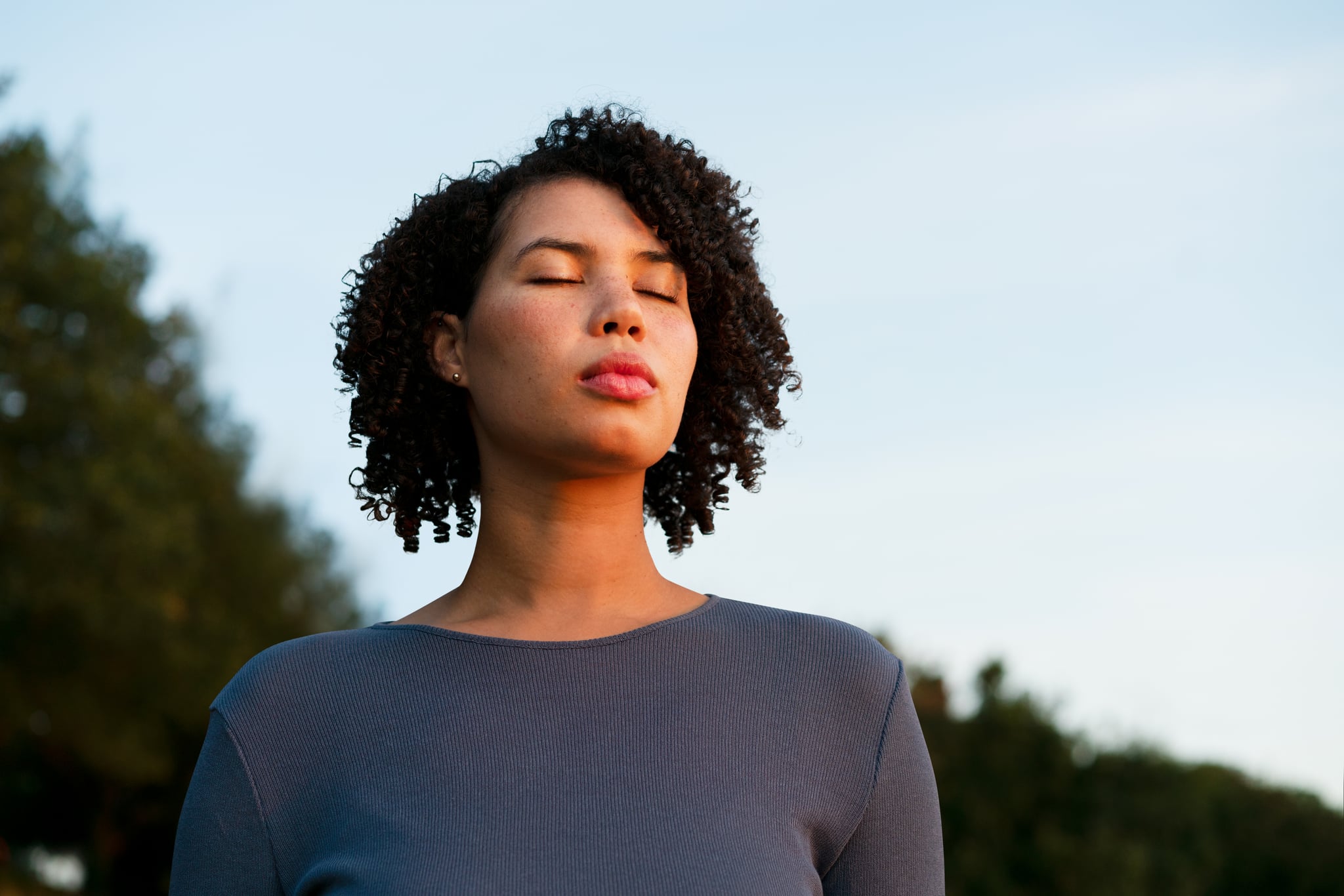 Woman with her eyes closed, grounding herself in nature. Woman with her eyes closed, grounding herself in nature.