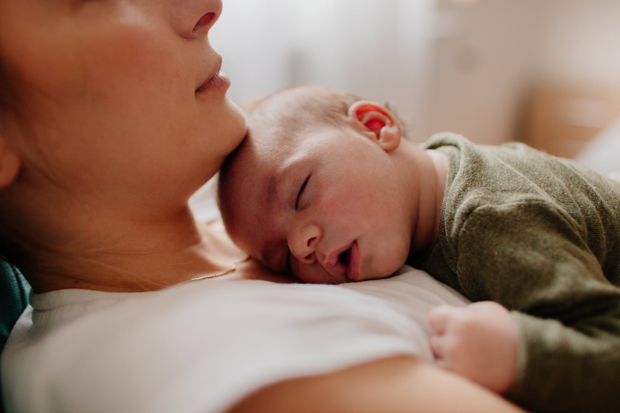 Photo of a young mother holding her newborn baby, while putting him to sleep