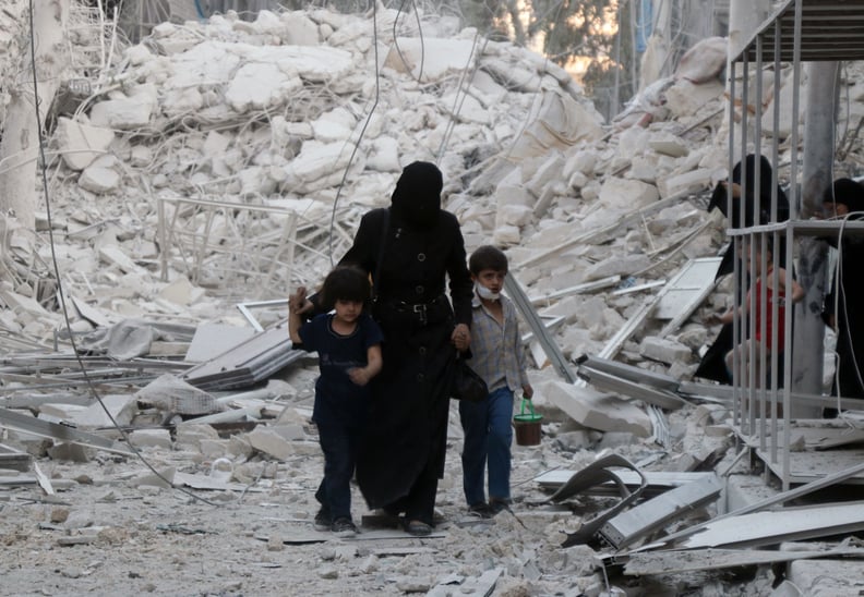 A woman and two children walk through rubble in Aleppo.