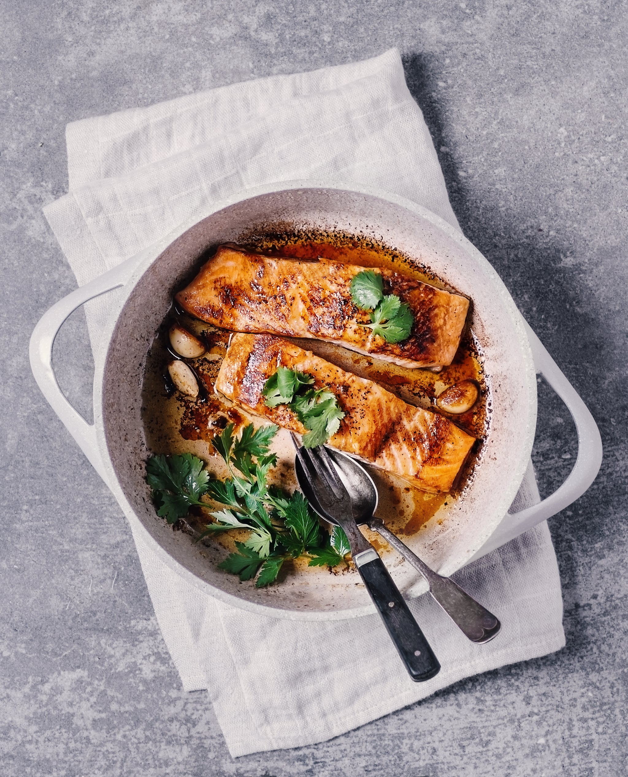 Seared salmon in a cooking pan on gray background