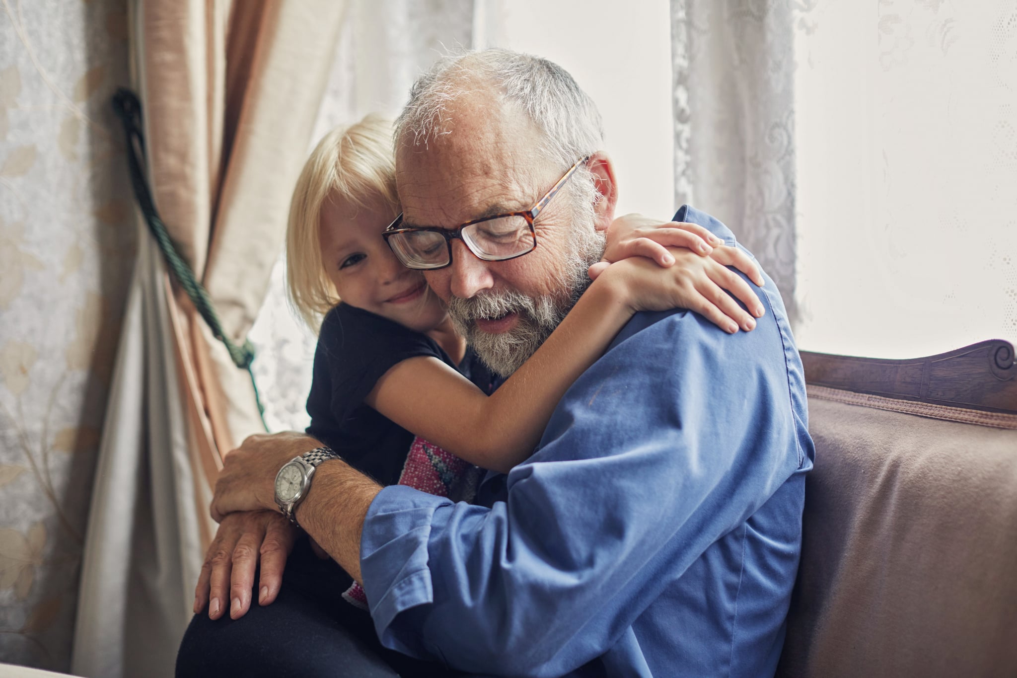 Happy smiling granddaughter hugging her grandfather