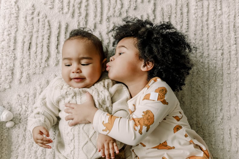 a sister and brother lying on a blanket at home