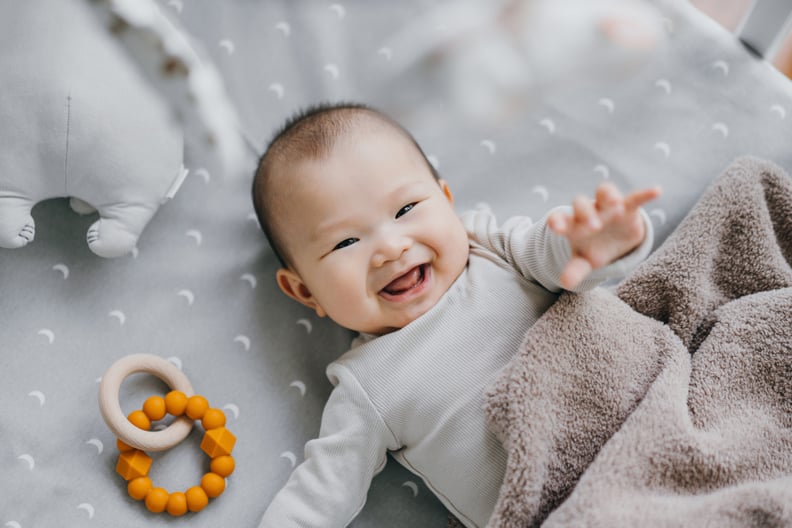 Baby Girl Smiling on Bed and Reaching Hand Out
