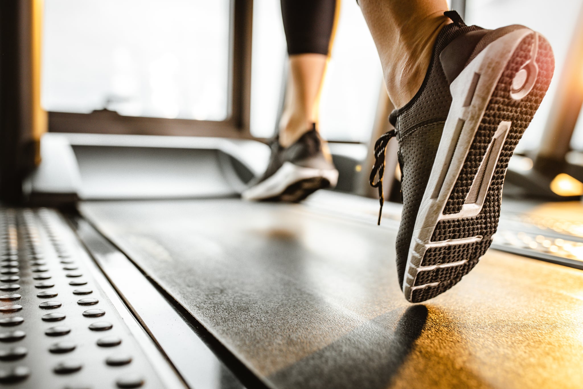 Close up of sole of sneakers of unrecognisable athlete jogging on a treadmill.