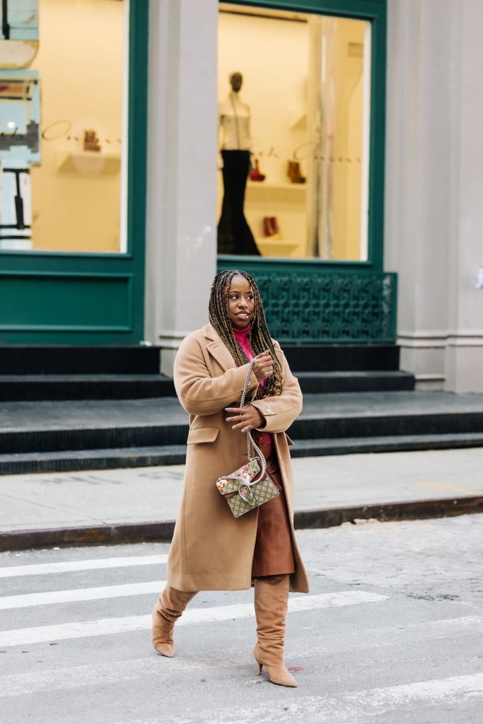 Jessica Andrews wearing neutral boots from Flor de Maria, a camel Aritzia coat and brown leather midi skirt — finished with a hot pink turtleneck sweater.