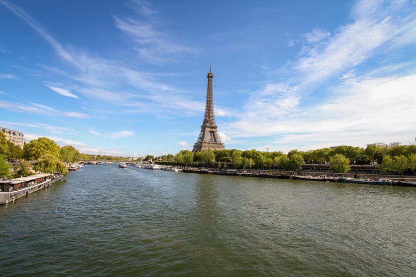 The Seine river and the Eiffel tower on a bright day in Paris.