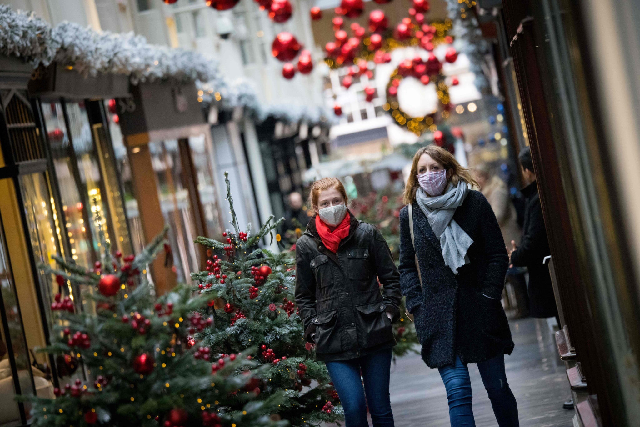 Pedestrians wearing face masks due to the COVID-19 pandemic, walk past Christmas-themed window displays inside Burlington Arcade in central London, on November 23, 2020. - Prime Minister Boris Johnson's latest plan is to roll out mass testing to the hardest-hit areas, hoping to make enough inroads to be able to relax social restrictions in time for Christmas. (Photo by Tolga Akmen / AFP) (Photo by TOLGA AKMEN/AFP via Getty Images)