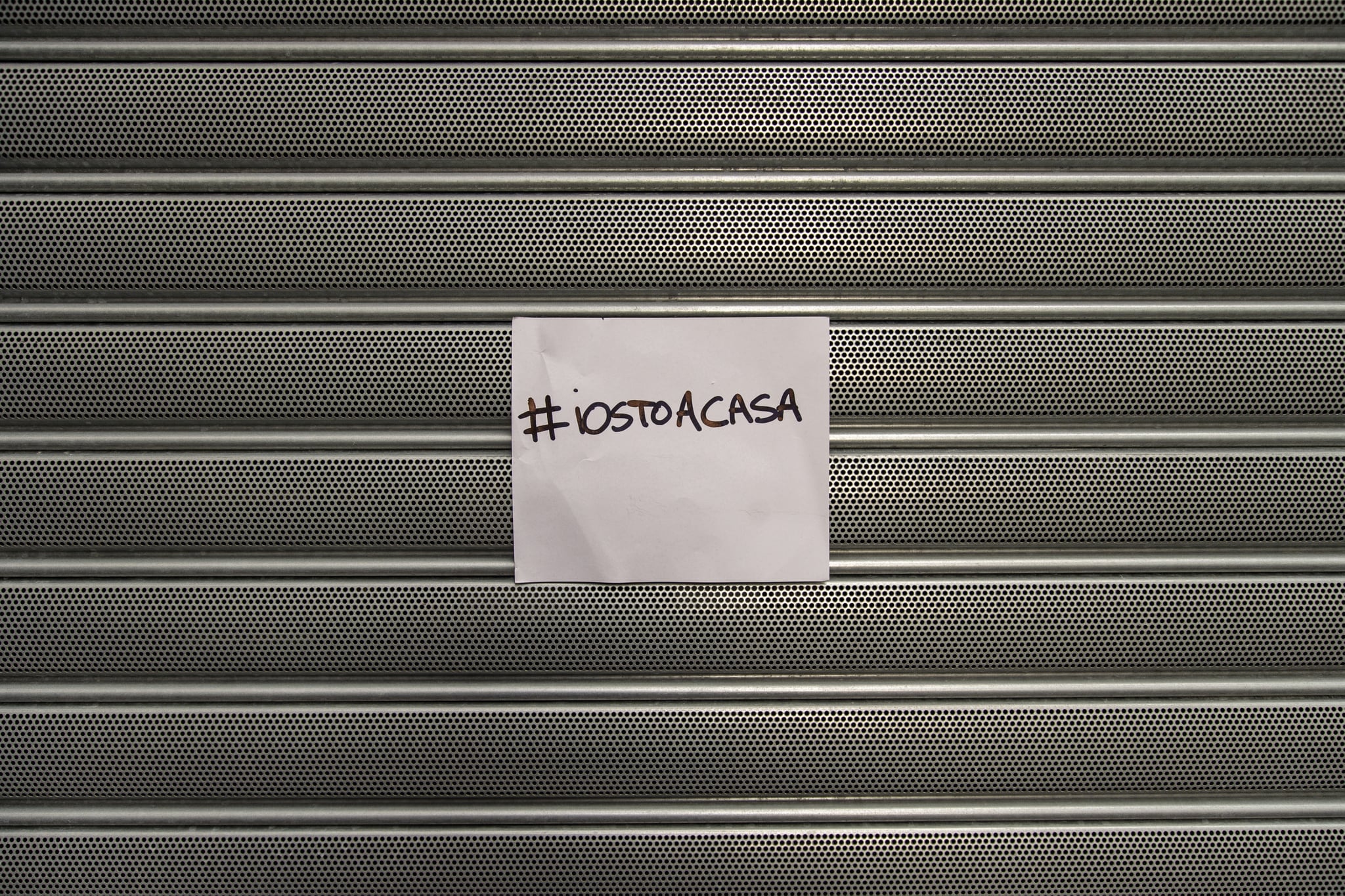 SALERNO, ITALY - MARCH 10: The shutter of a shop closed with a sign that reads #iorestoacasa (I'm staying at home) on March 10, 2020 in Salerno, Italy. In Italy after the extension of the red zone to the entire peninsula due to the spread of the coronavirus, with considerable restrictions for all citizens and with the circulation permit only in case of work, health and for the purchase of primary goods, the bulletin updated by the Civil Protection has been released: Covid-19 counts 10,149 of which 1,004 were cured, while 631 people died after being positive for the virus. (Photo by Ivan Romano/Getty Images)