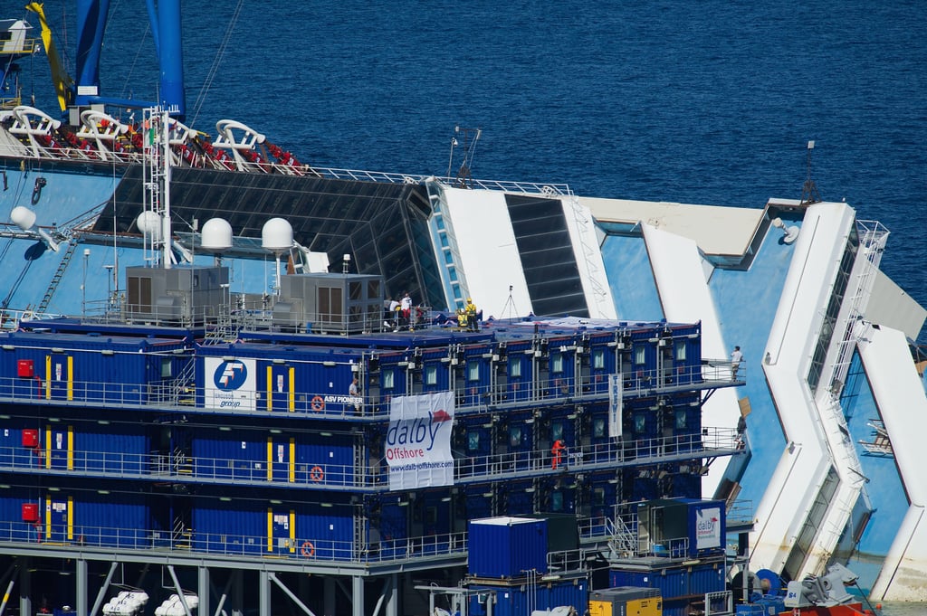 Workers stood on platforms beside the ship.
