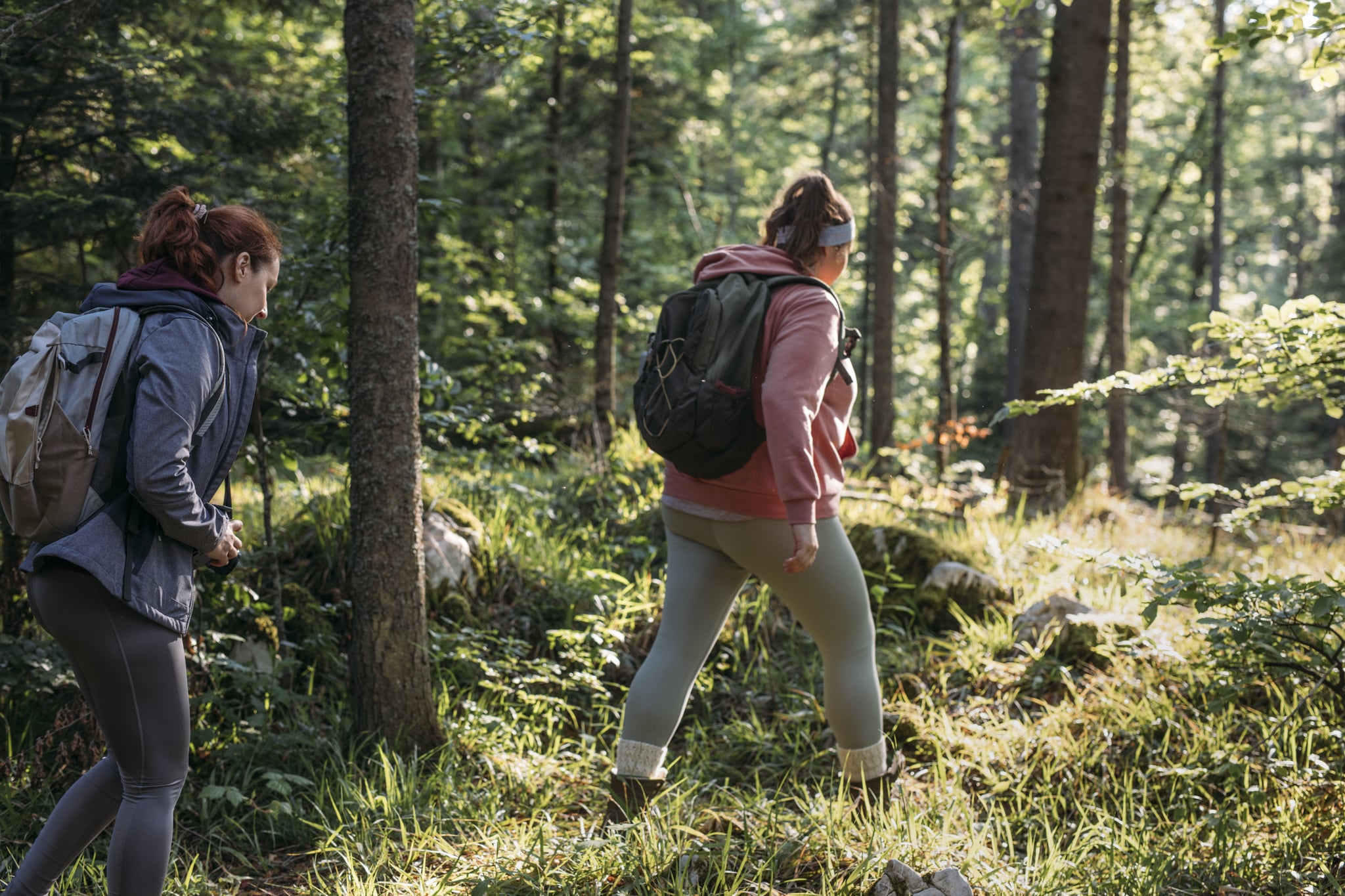 Two happy female friends talking while walking in the forest