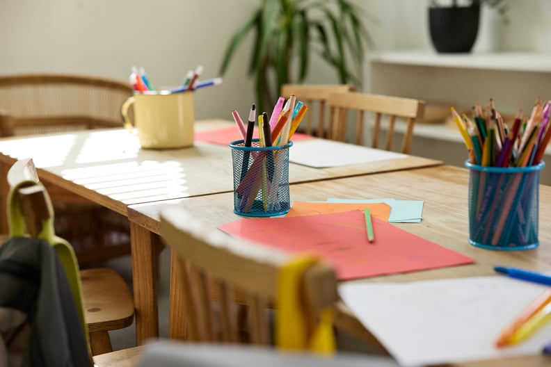 Colored pencils kept in containers on table near papers in empty classroom at school