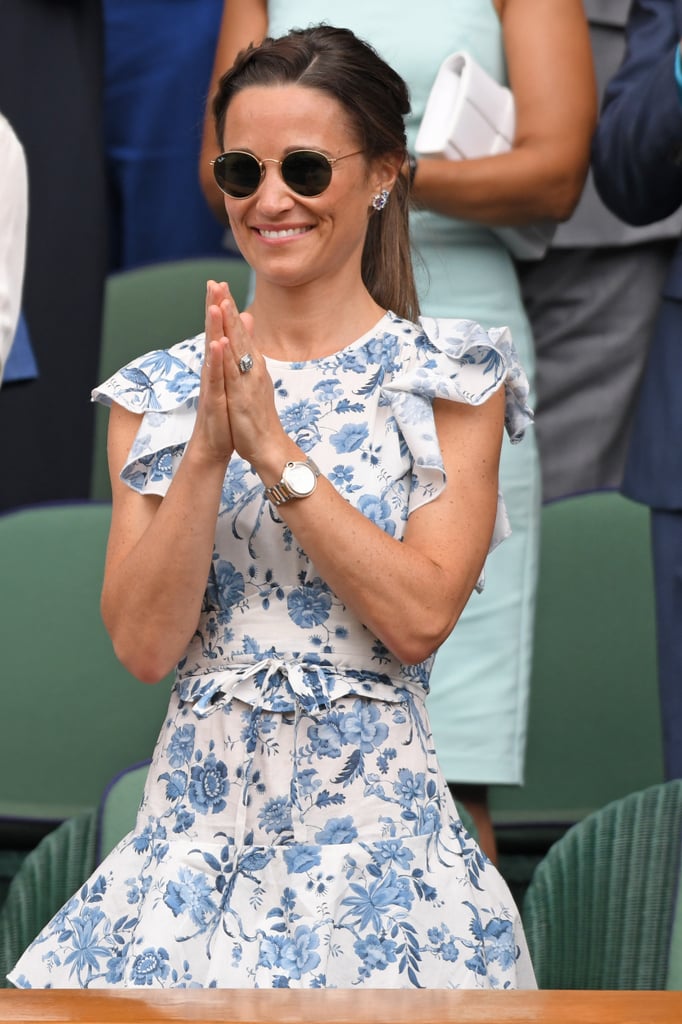 When it comes to Wimbledon, Pippa Middleton is all about florals — and we're 100 percent on board. Just days after she donned a sunshine yellow Ganni wrap-dress for the tennis tournament, she made another appearance at the event in a similarly garden-esque outfit. This time around, she was joined by her sister, Kate Middleton, and Kate's sister-in-law, Meghan Markle. All three women showed off their unique style during the Wimbledon final, and Pippa kept things darling and dainty with her classic look. 
For their girls day out, Pippa chose an Anna Mason London ruflette sleeveless midi dress from the brand's Spring 2019 collection. She paired the simply stunning, modest ensemble with her trusty blue Penelope Chilvers espadrille wedges, a familiar style that she wore to Wimbledon in 2018. She tied everything together with a braid in her hair, a pair of round wire sunglasses, a white leather watch, matching floral earrings, and of course, her gorgeous engagement ring. 
Keep reading to see even more photos of Pippa's sophisticated Summer look. Fingers crossed that this fun and fashionable trio takes another outing together soon.