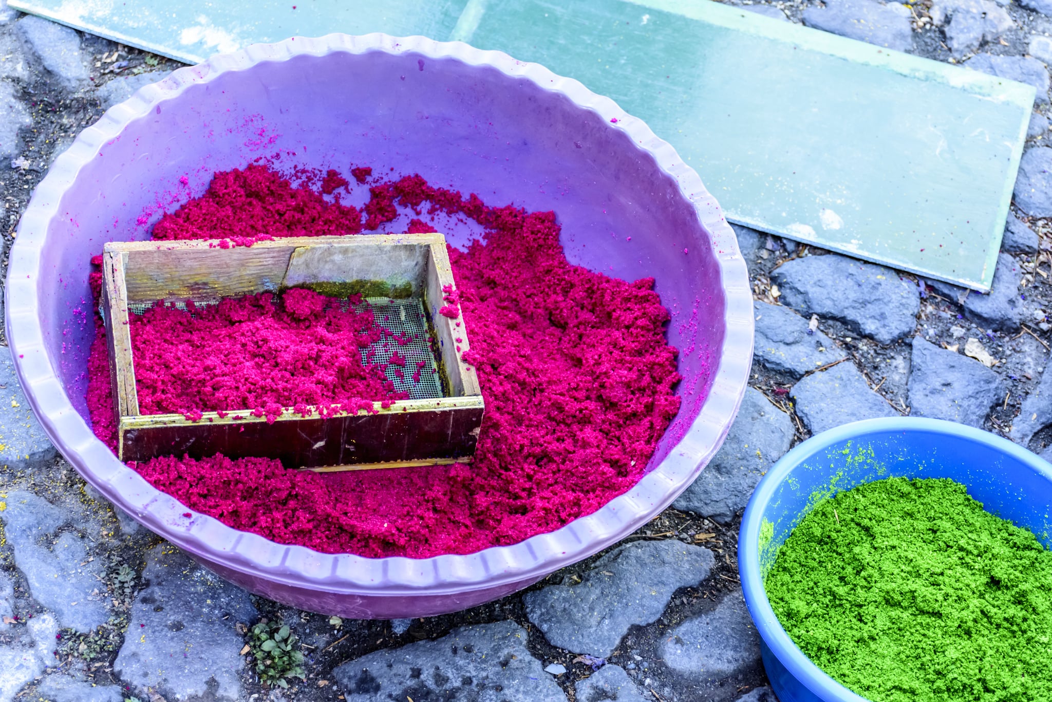 用染色木屑和筛子制成的容器，在拉丁美洲最著名的圣周庆祝活动的镇上制作棕枝主日游行地毯