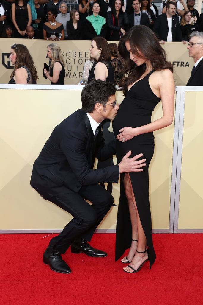 John Stamos is ready to be a father. The 54-year-old actor walked the red carpet at the 2018 SAG Awards with his pregnant fiancée, Caitlin McHugh, and stopped to kiss her belly before posing for more photos. The sweet moment comes after what has been a stellar year for the Fuller House star. John and Caitlin got engaged last October before revealing that they would be expecting their first child later this year. Read on to see more photos from their sweet night out ahead.