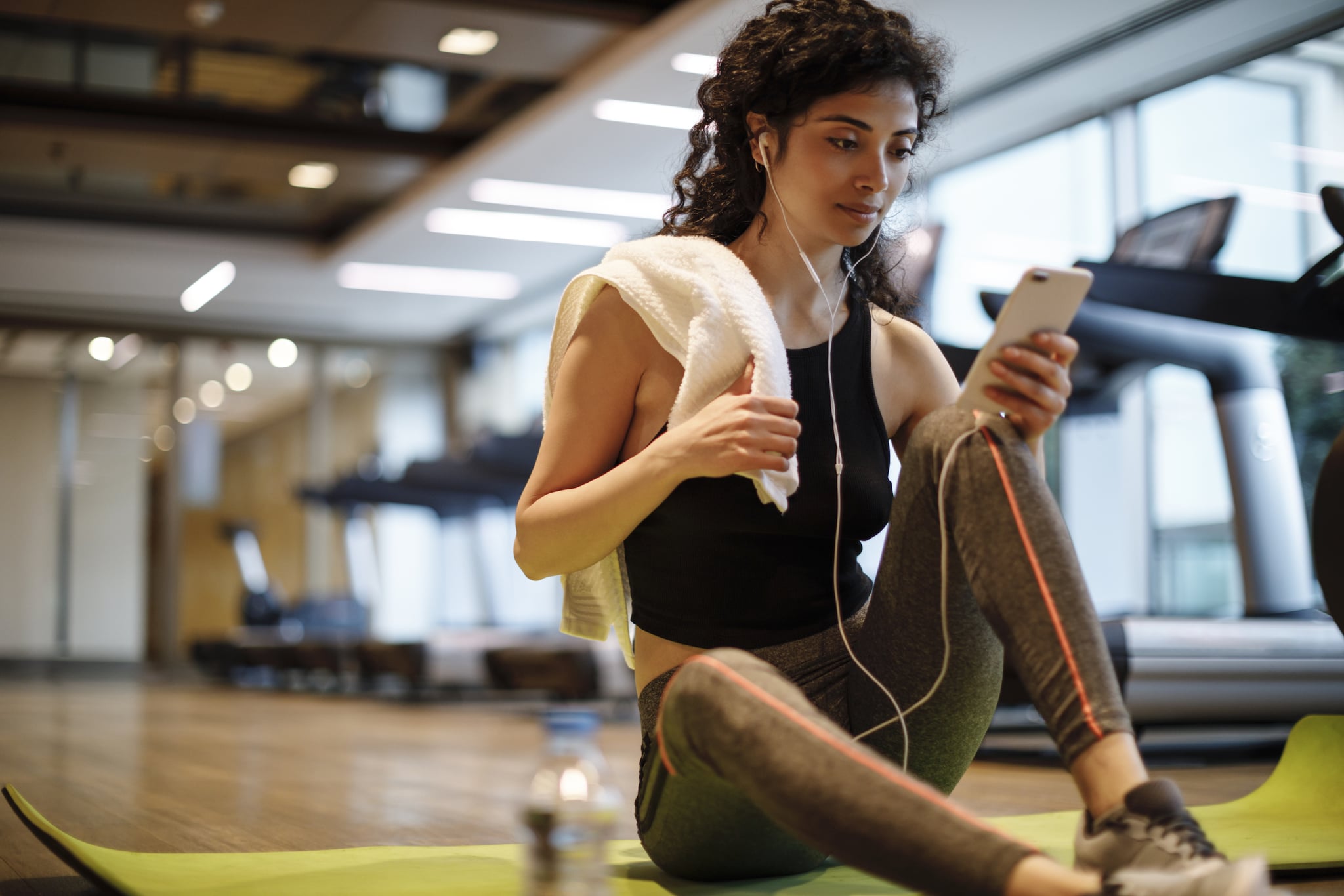 Young woman listening to music over cell phone at the gym