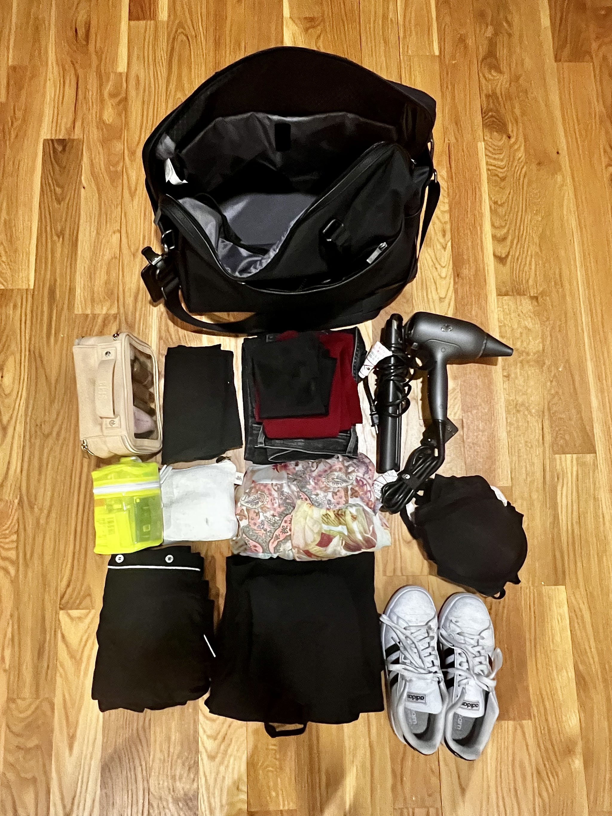 The Open Story Weekender Bag packed with travel essentials including sneakers, makeup bag, skin-care kit, and toiletries pouch, a pair of jeans, a sweater, my undergarments, a travel hair dryer, and a straightener, a dress, a jumpsuit, a pair of pajamas, a pair of leggings, and two tops.