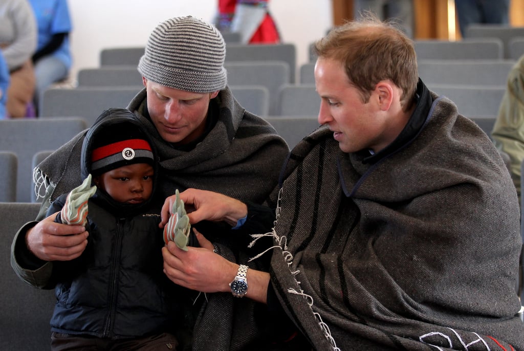 Harry and Will helped a little boy put gloves on during a visit to a child education centre in Lesotho in June 2010.