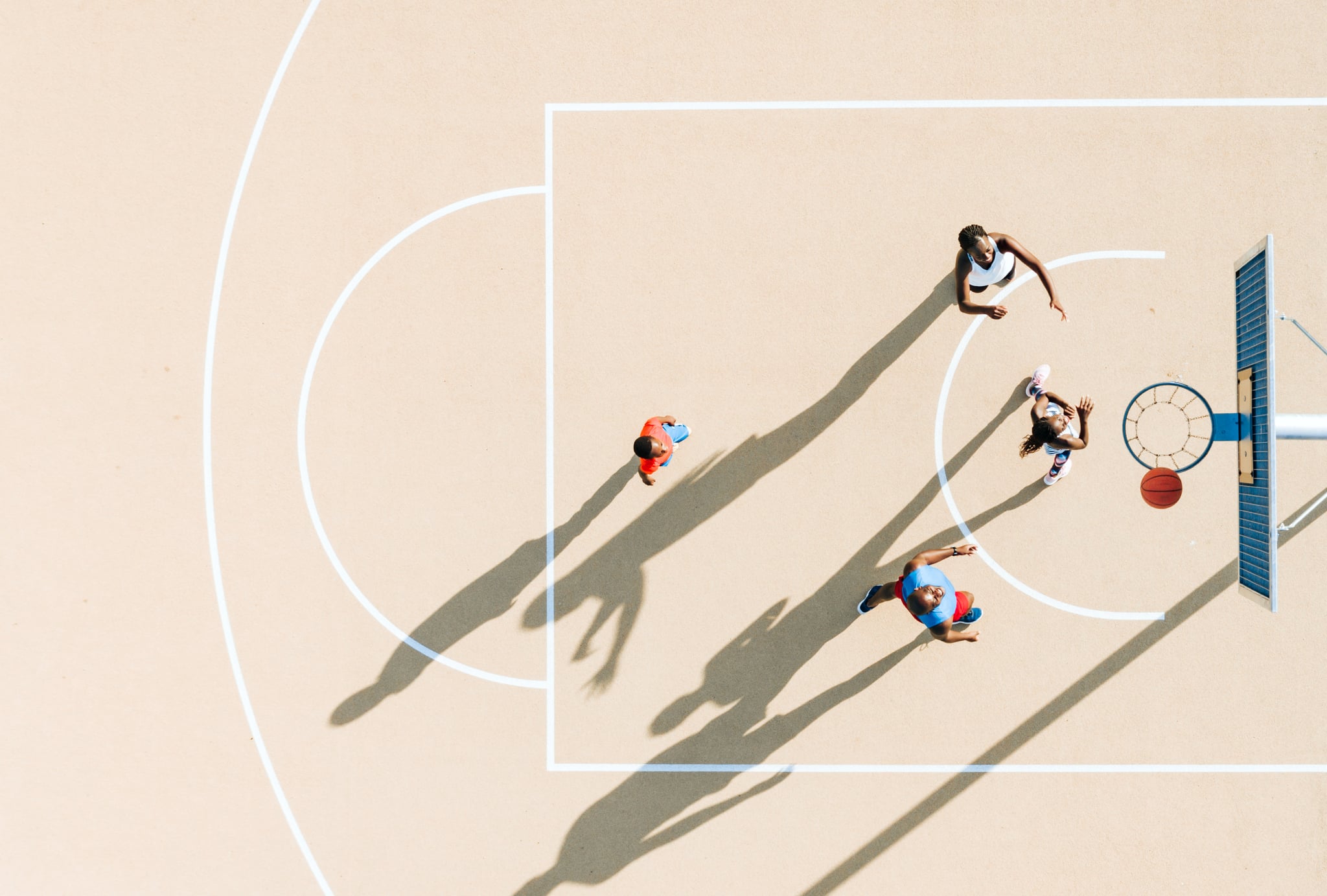 drone view on mother, father and two kids fighting for basket ball on public sports court