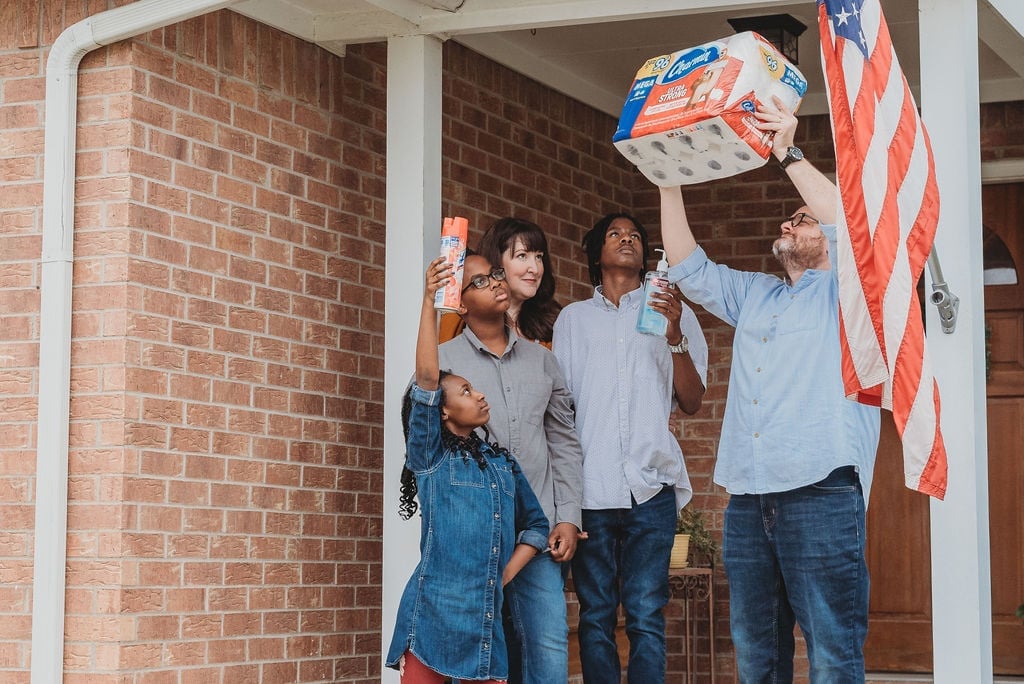 Sara Ester, a photographer from Texas, captured how families were social distancing in the beginning of the pandemic. She put a hopeful spin on a photo series called, "Front Porch Sessions," which depicts families with signs or holding household items like toilet paper and disinfectant. 
"Amid all the COVID-19 stuff going on I asked if families would be interested in a quick five-minute session on their front porches to document what a crazy experience it has been to be quarantined at home," Sara told POPSUGAR. "The people participating ran with it! So many families made funny or encouraging signs, showed up in their pajamas or yoga pants, and just really embraced the whole 'quarantine chic' idea. It was really reaffirming to see how everyone is in the same boat. We're all just trying to do the best we can with a crappy situation!"