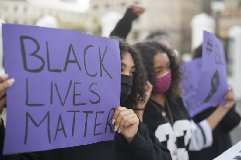 Protestors hold up placards during a protest against police violence, at the gates of the South African Parliament in Cape Town, on June 3, 2020. - This protest is in solidarity with the Black Lives Matter movement in the United States of America (USA), a