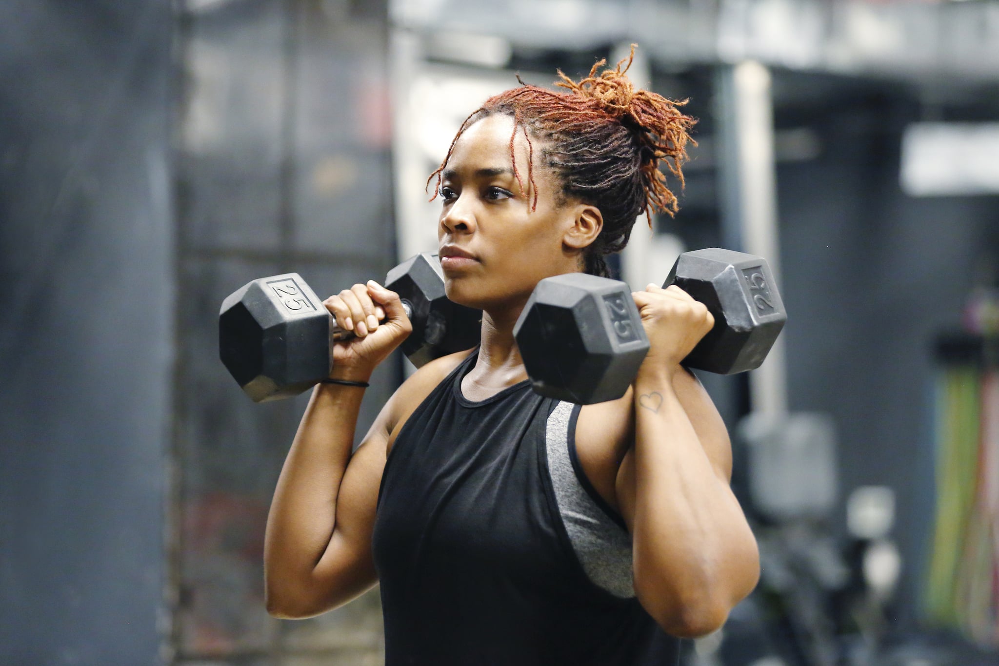 Wasit up image of a fit, young African American woman working out with hand weights in a fitness gym.