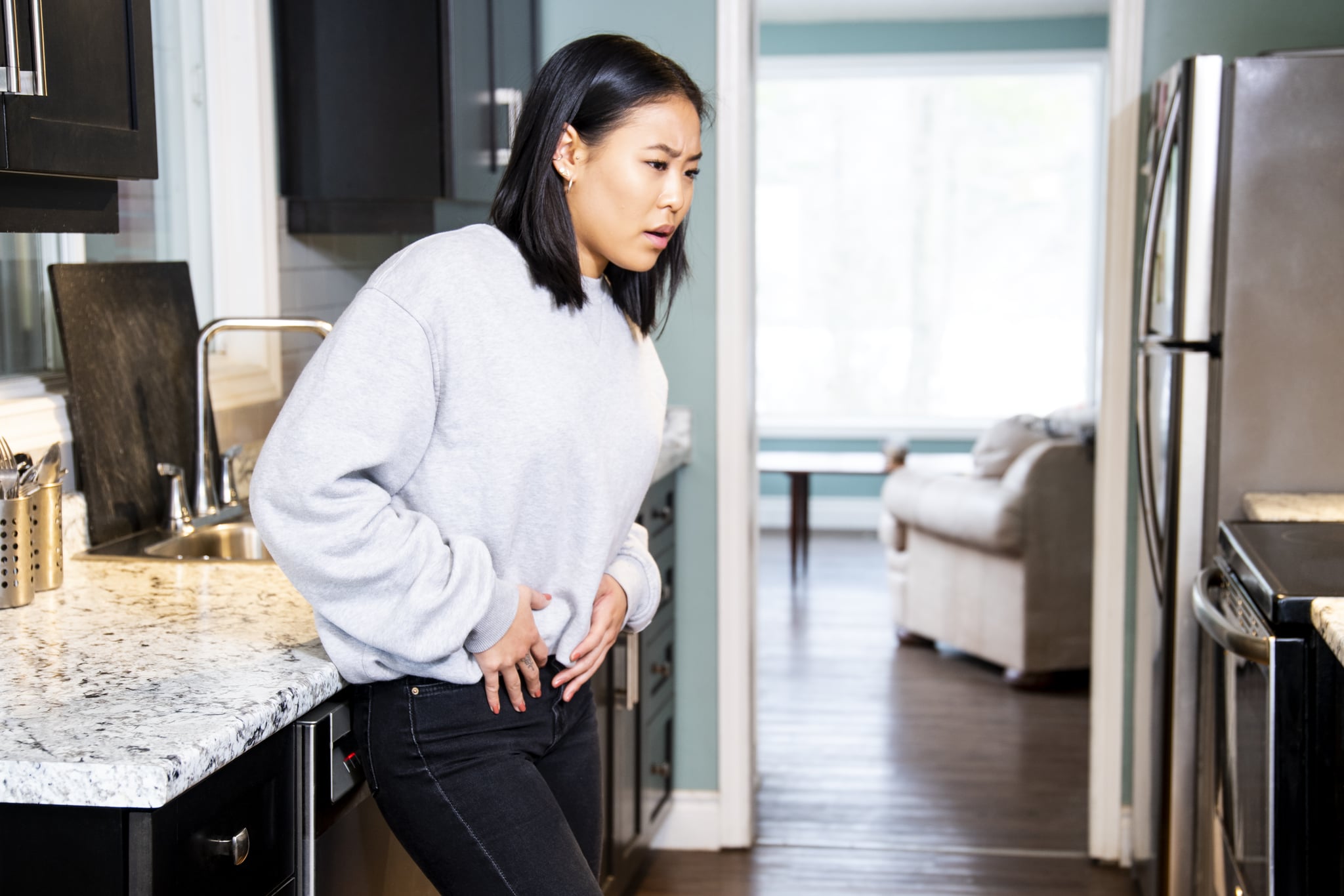 A young woman experiencing pelvic discomfort, she is grimacing in pain.