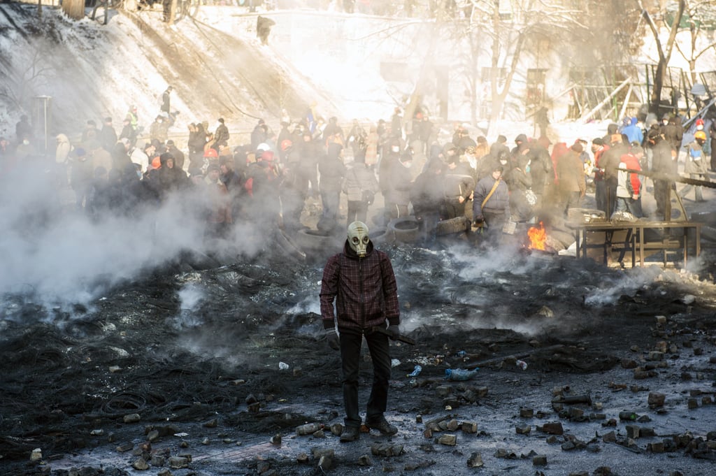 A protester wearing a gas mask stood among charred garbage as the group clashed with policemen.